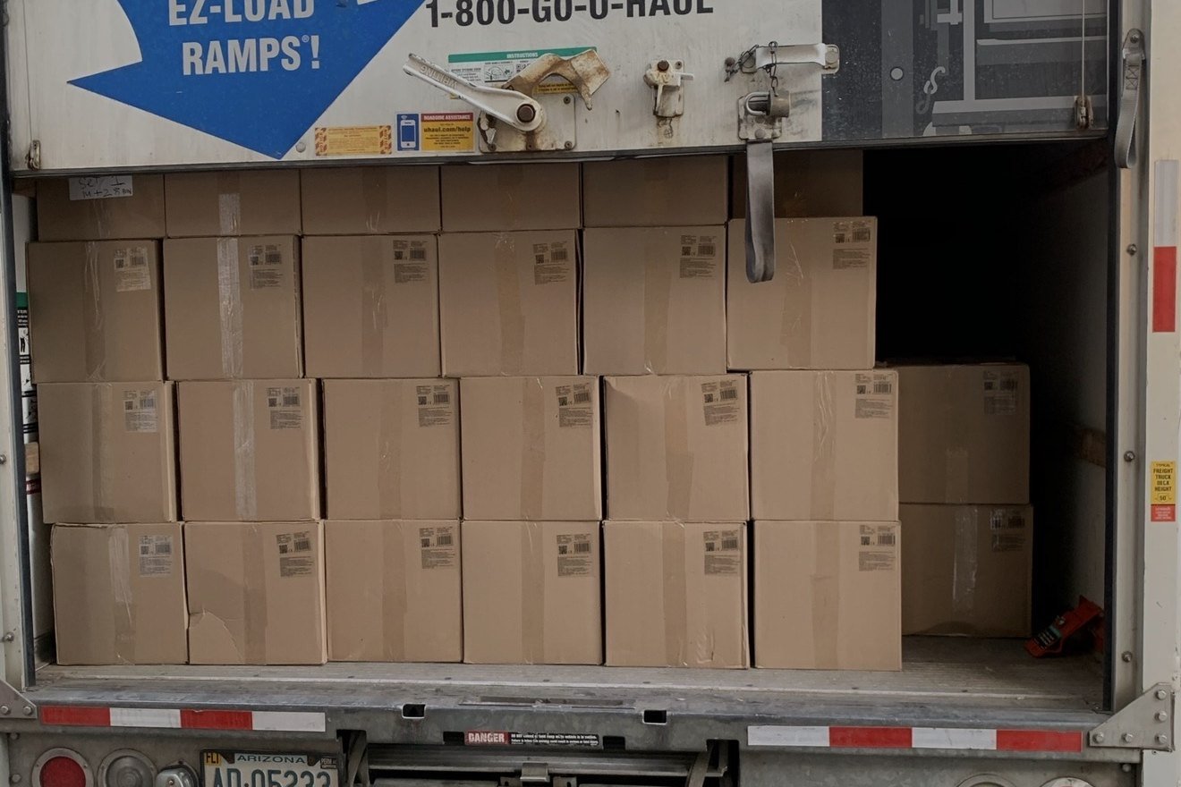 Rear of a U-Haul truck packed with uniform cartons nearly to the roof.