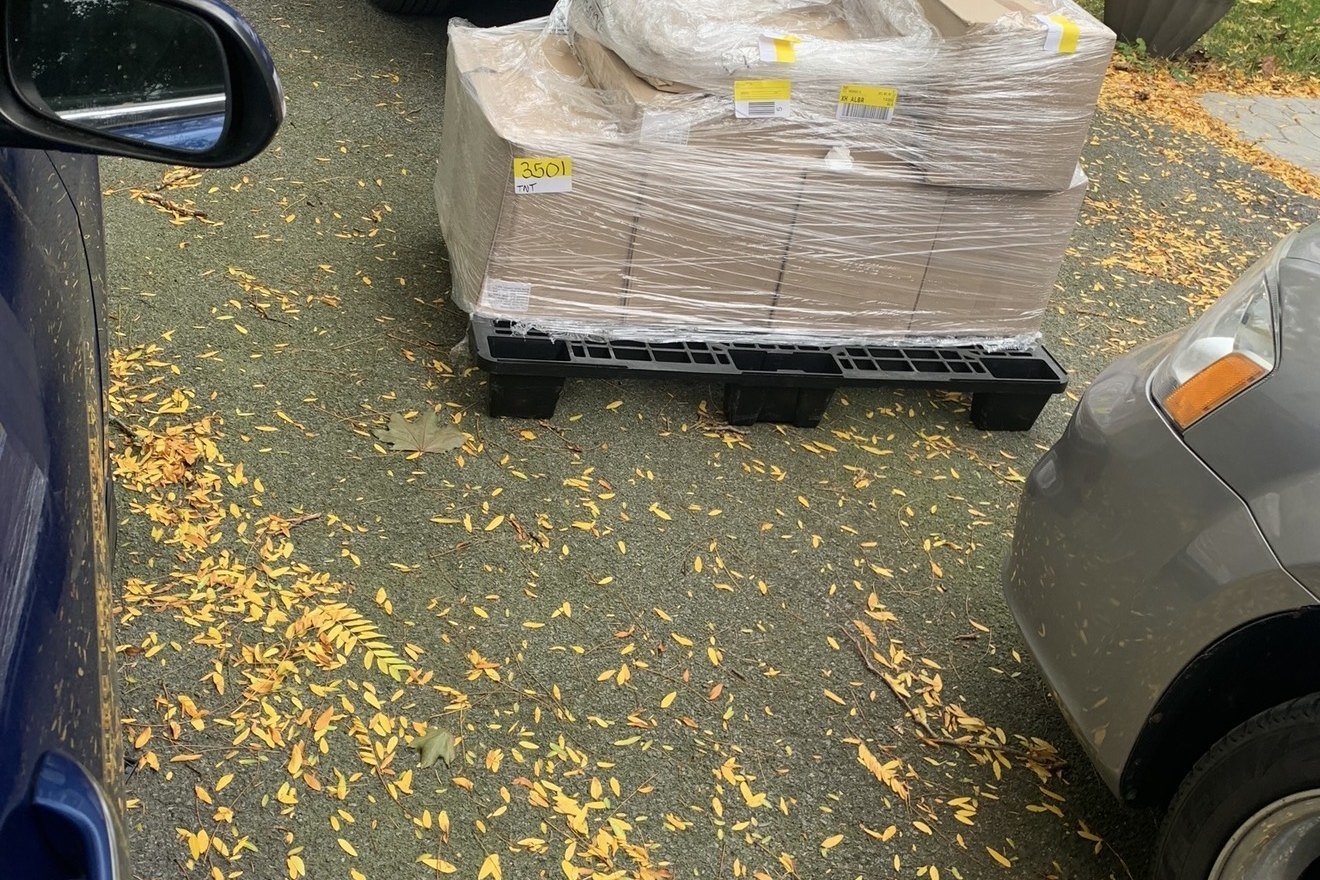 A pallet of shrink-wrapped outgoing cartons staged in a residential driveway.